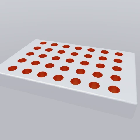 A white slab drilled with thirty-five holes, each bore lined in orange because the cutter carried its own material.